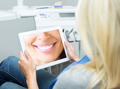 Woman looking at her cosmetic dentistry plan on tablet compter