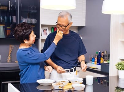 a couple cooking together and feeding each other bites of food