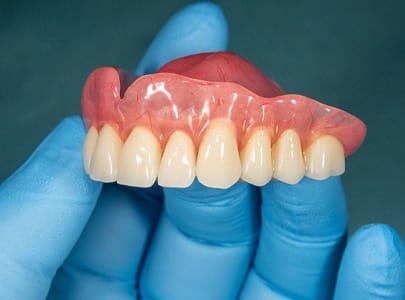a dentist holding natural-looking full dentures
