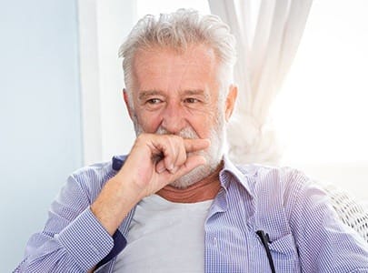 Older man who need to replace missing teeth covering his mouth