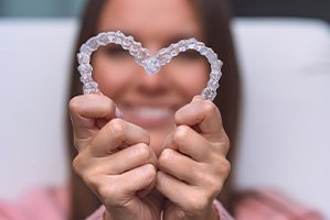 Woman holding SureSmile in the shape of a heart