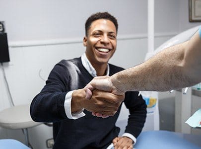 Man shaking hands with dentist during family dentistry appointment