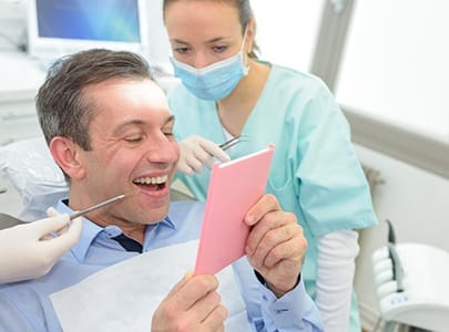 Male patient admiring smile after receiving dental crown
