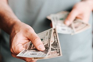 Man’s hand extending cash for payment