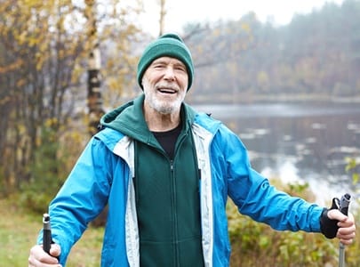 a happy retired person taking a hike by a lake