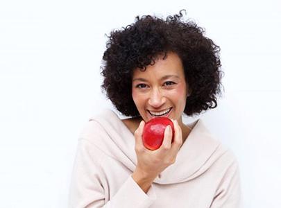 woman with dentures in Cary biting into a red apple 