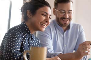 Woman at desk with coworker, smiling with dental implants in Cary, NC