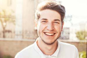 Young man outside smiling with dental implants in Cary, NC