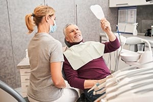 Senior dental patient admiring his dental implant restorations