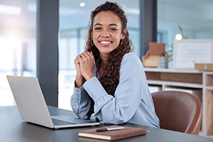 Woman smiling while working on laptop in office