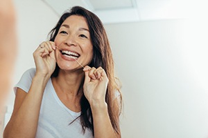 Woman smiling while flossing her teeth