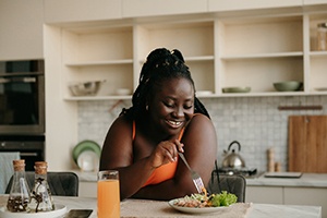 Woman smiling while eating healthy meal at home