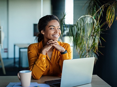 Woman smiling while working on laptop at home