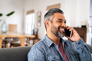 Man smiling while talking on cellphone at home