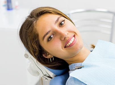 Woman in dental chair smiling after antibiotic therapy