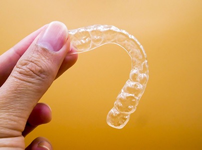 Close up of SureSmile clear aligner with yellow background