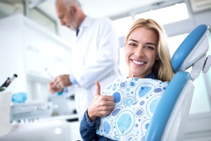 woman in dental chair giving thumbs up