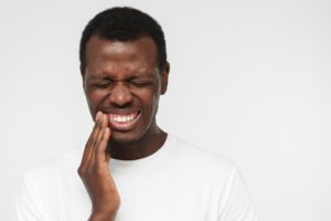 a person holding their mouth because they have a toothache and need to visit an emergency dentist in Cary