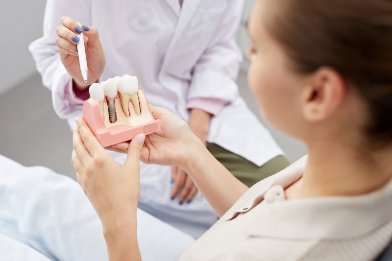 Dentist pointing to dental implant model