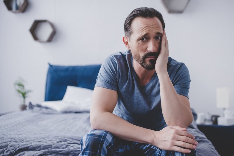 A man with a toothache sitting on a bed