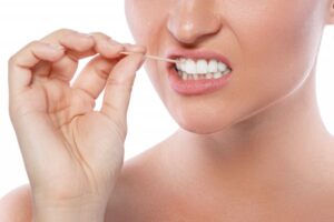 Woman using toothpick to get a stuck piece of food in her mouth