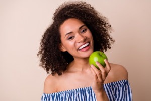 a woman smiling and eating an apple